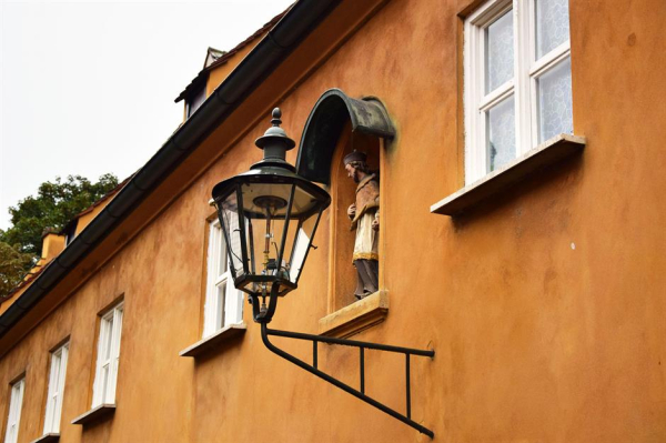 Газовый фонарь и статуя святого на фасаде здания.