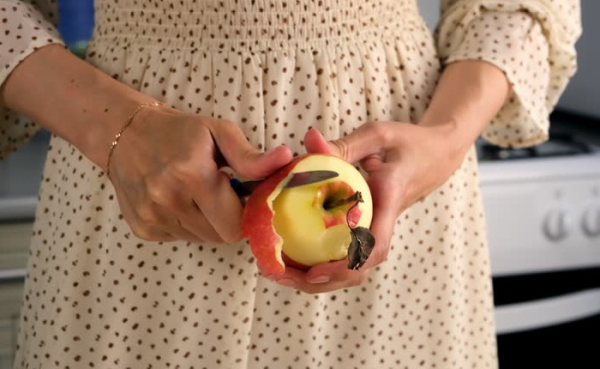 Девушка чистить яблоко. / Фото: istockphoto.com